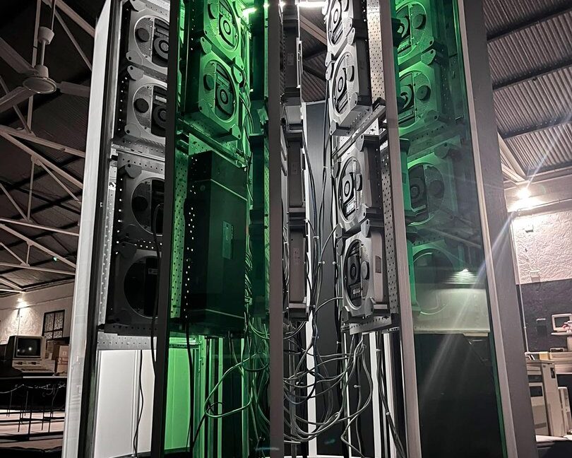 A vertical photo showing the size of the Cray-1 replica project. A large C-shaped tower stands lit up with green accent lighting.